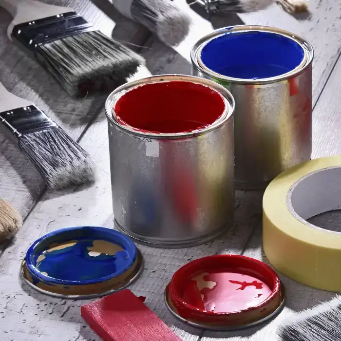red and blue paint cans open near brushes and other supplies