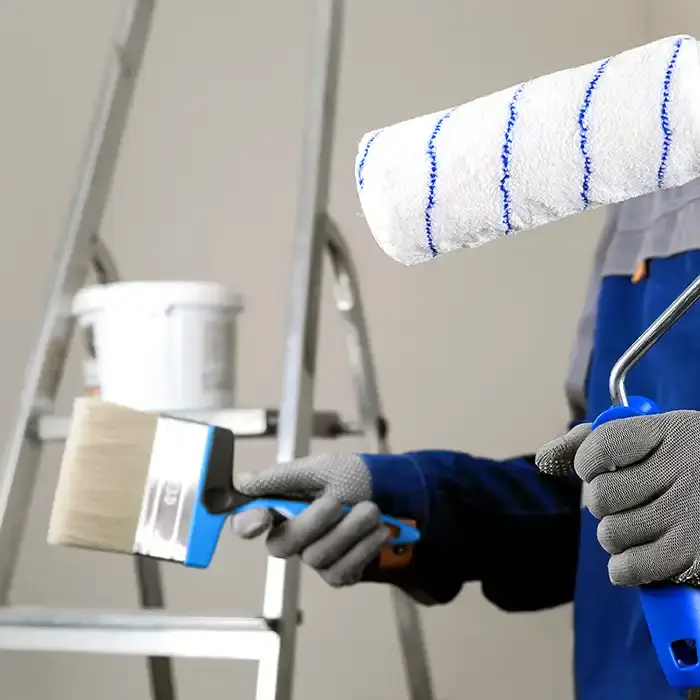 painter holding brush and roller near ladder